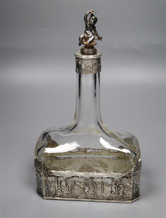 A late 19th/early 20th century German Hanau white metal mounted glass decanter, with figural stopper, 23.8cm.
